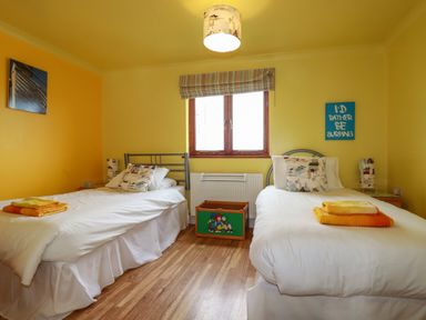 A bedroom with two single beds and a window at Sunflower Cottage in St Issey