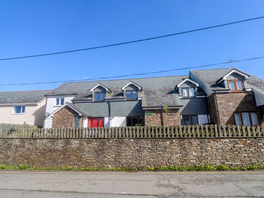 A house with a stone wall and a fence at Sunflower Cottage in St Issey