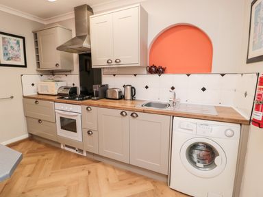 A kitchen with wooden countertops washing machine oven microwave and sink at Simonside Apartment in Rothbury