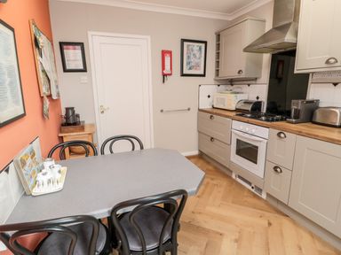 A kitchen with a dining table and chairs a stove microwave toaster and coffee machine at Simonside Apartment in Rothbury