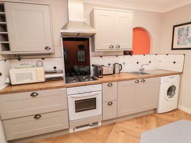 A kitchen with a microwave toaster washing machine stove and sink at Simonside Apartment in Rothbury
