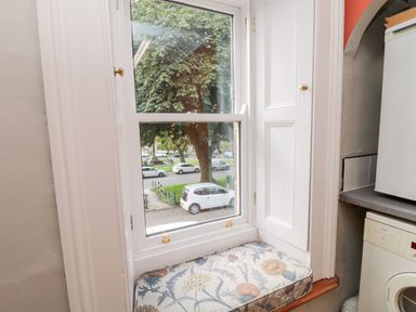 A window with a floral cushion on the sill and cabinetry beside it in a laundry room at Simonside Apartment in Rothbury