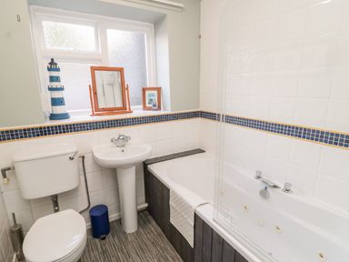 A bathroom with a toilet sink and bathtub under a frosted window at Simonside Apartment in Rothbury