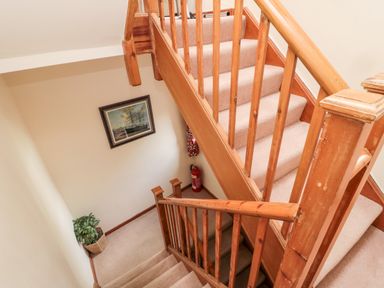 A wooden staircase with beige carpet a framed ship painting a potted plant and a fire extinguisher at Simonside Apartment Rothbury