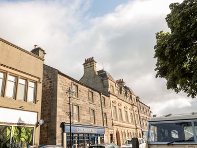 A street view with stone buildings including one named The Narrow Nick and parked cars under a partly cloudy sky
