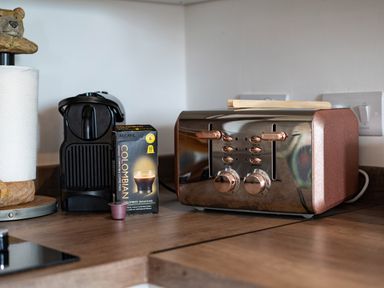 A kitchen countertop with a toaster, coffee machine, coffee pods, and a paper towel holder at Bear Cottage in Chacewater near Truro