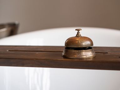 A brass service bell on a wooden board over a white bathtub at Bear Cottage in Chacewater near Truro