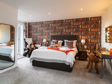 A bedroom with a bed a chair a desk and a large mirror at Bear Cottage in Chacewater near Truro