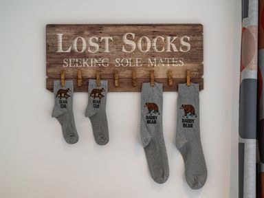 A wooden sign with clips holding grey socks labelled bear cub and daddy bear at Bear Cottage in Chacewater near Truro