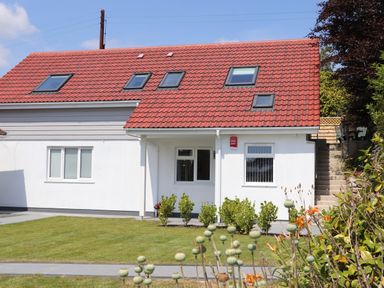 A house with a red tiled roof and white walls with windows and garden at The Crest in Helston