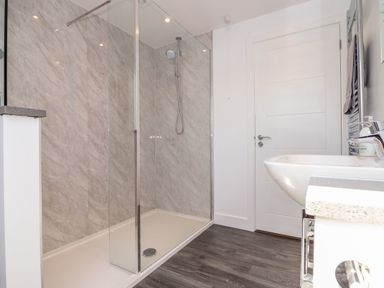 A bathroom with a walk-in shower sink and door at The Crest in Helston