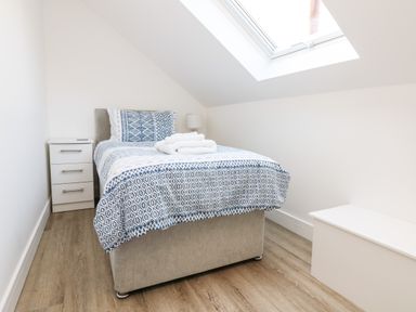 A small bedroom with a single bed a bedside table a skylight and a storage bench at The Crest in Helston