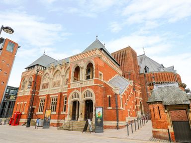 An exterior view of a historic red brick building with arched doorways and stone detailing at Boosters Lodge in Stratford-upon-Avon