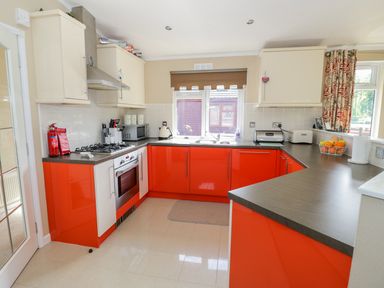 A kitchen with red lower cabinets beige upper cabinets and a window above the sink at Booster's Lodge in Stratford-upon-Avon