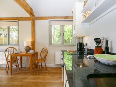 A kitchen with wooden chairs and table and kitchen counter with utensils at The Lodge at Mortons in Hankerton