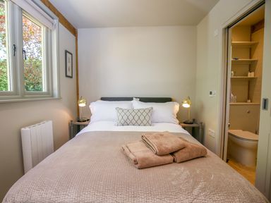 A bedroom with a bed and a window next to an ensuite bathroom at The Lodge at Mortons in Hankerton