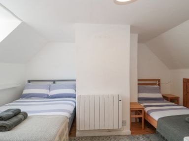A bedroom with a double bed and a single bed separated by a white radiator at Abbey Cottage Montacute
