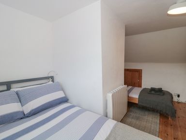 A bedroom with two beds separated by a partial wall and a heater on a wooden floor at Abbey Cottage Montacute