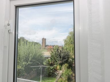 A view of trees and a tall building seen through a window at Abbey Cottage Montacute