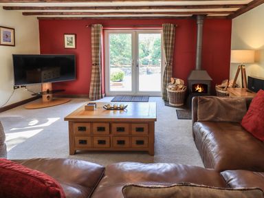 A living room with a leather sofa a wooden coffee table a fireplace and a television at Ellerbeck Bridge Underbarrow near Kendal