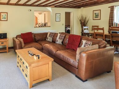 A living room with a brown leather sofa and wooden coffee table at Ellerbeck Bridge in Underbarrow near Kendal