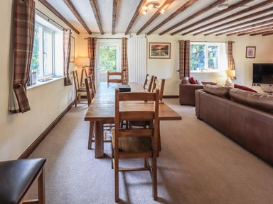 A dining and living room with a wooden dining table and chairs and leather sofas at Ellerbeck Bridge in Underbarrow near Kendal