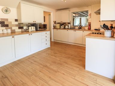 A kitchen with wooden floor white cabinets and various kitchen appliances at Ellerbeck Bridge in Underbarrow near Kendal