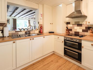 A kitchen with white cabinets wooden countertops a sink and an oven at Ellerbeck Bridge Underbarrow near Kendal