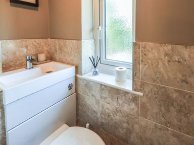 A bathroom sink with a faucet toilet paper and a window with frosted glass at Ellerbeck Bridge in Underbarrow near Kendal