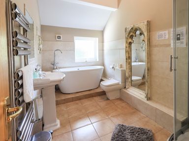 A bathroom with a bathtub sink toilet large mirror and towel rack at Ellerbeck Bridge Underbarrow near Kendal
