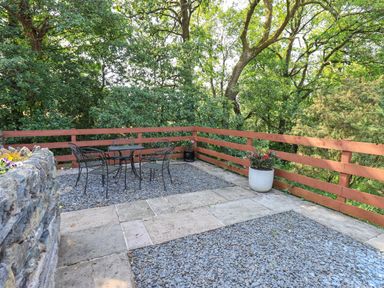 An outdoor patio with a metal table and four chairs surrounded by a wooden fence at Ellerbeck Bridge Underbarrow near Kendal