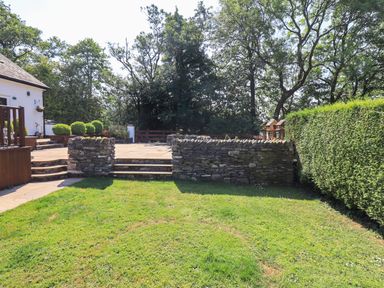 A garden with green grass stone wall steps and hedge at Ellerbeck Bridge in Underbarrow near Kendal