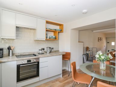 A kitchen with stove oven countertop and dining table with chairs at Troopers Cottage in Frome