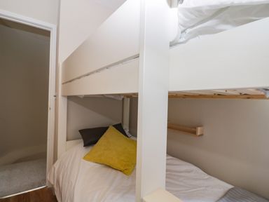 A small bedroom with a white bunk bed and pillows at Troopers Cottage in Frome