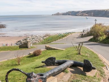 A large anchor on grass near a road with benches and a beach in the background at Sea-u-Soon in Runswick Bay