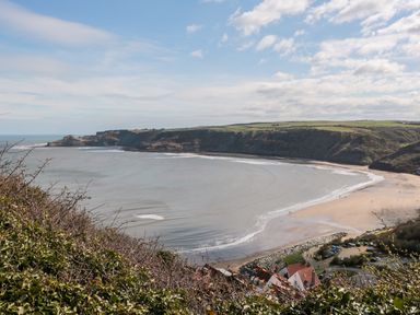 A coastal bay with a sandy beach cliffs and some buildings at Sea-u-Soon in Runswick Bay
