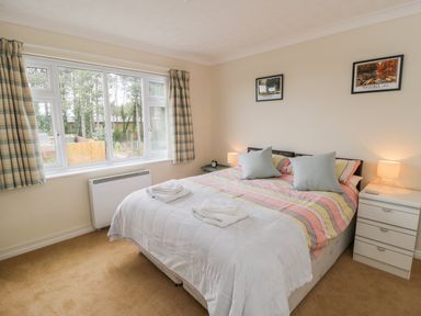 A bedroom with a double bed two bedside tables with lamps and a window with curtains at Sea-u-Soon in Runswick Bay
