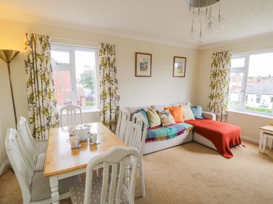 A living room with a dining table and chairs and a sofa with cushions at Sea-u-Soon in Runswick Bay