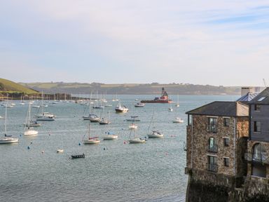 A harbor with sailboats and a stone building by the water at Toadstools in Rame Cross near Penryn