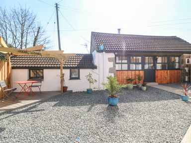 A gravel courtyard with potted plants and a seating area with table and chairs at Toadstools Rame Cross near Penryn