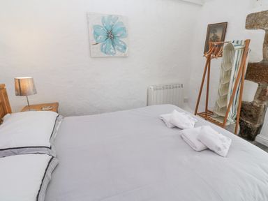 A bedroom with a bed lamp picture hangers and folded towels at Toadstools in Rame Cross near Penryn