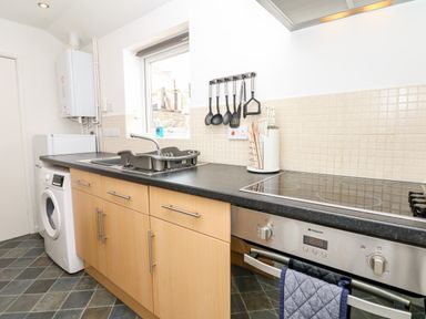 A kitchen with appliances wooden cabinets and kitchen utensils at Quayside View in Brixham