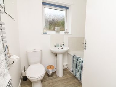 A bathroom with a toilet sink bathtub striped towel and window at Quayside View in Brixham