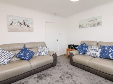 A living room with two sofas with blue and white cushions and two paintings on walls at Quayside View in Brixham
