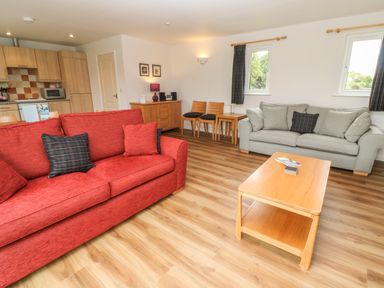 A living room with two sofas a wooden coffee table and a sideboard with chairs at 64 Waterside in Lanivet