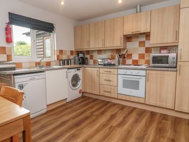 A kitchen with wooden cabinets a dishwasher washing machine oven microwave and kitchen utensils at 64 Waterside in Lanivet