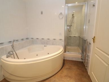 A bathroom with a corner bathtub and a shower enclosure at 64 Waterside in Lanivet