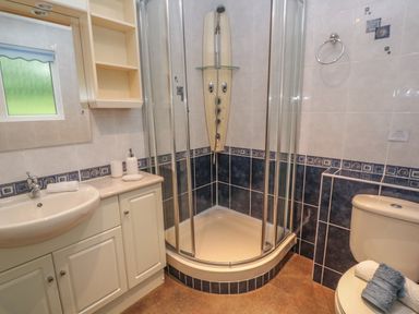 A bathroom with a corner shower enclosure a toilet with towels a sink with countertop and cupboards at 64 Waterside in Lanivet