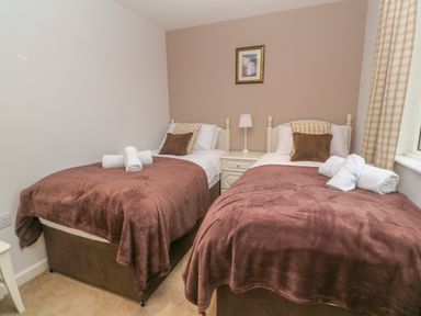 A bedroom with two single beds a nightstand with lamp and framed picture at 64 Waterside Lanivet