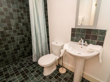 A bathroom with a toilet sink mirror and shower with curtain at Westmorland Cottage Grange-Over-Sands